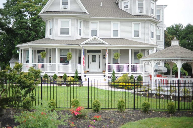 Victorian-style assisted living facility with a large porch and gazebo in the front yard.