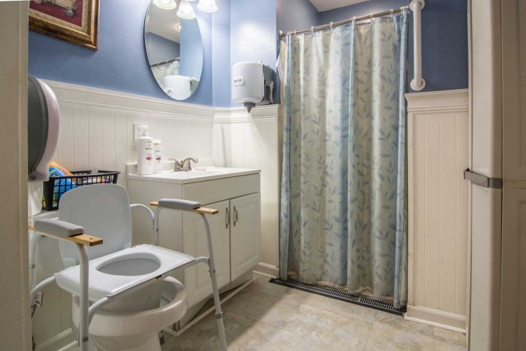 Accessible bathroom with a shower and a toilet chair in an assisted living facility.