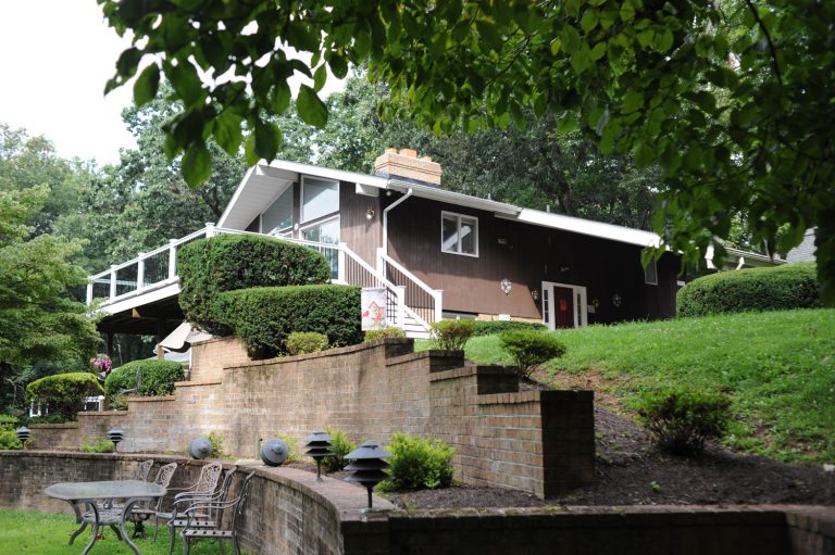 Exterior of an assisted living facility surrounded by trees and a spacious yard.